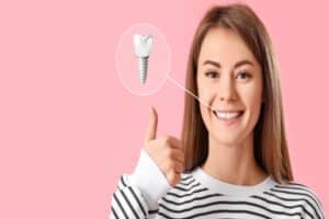 Image of a woman smiling and giving a thumbs up with an image of a dental implant next to her